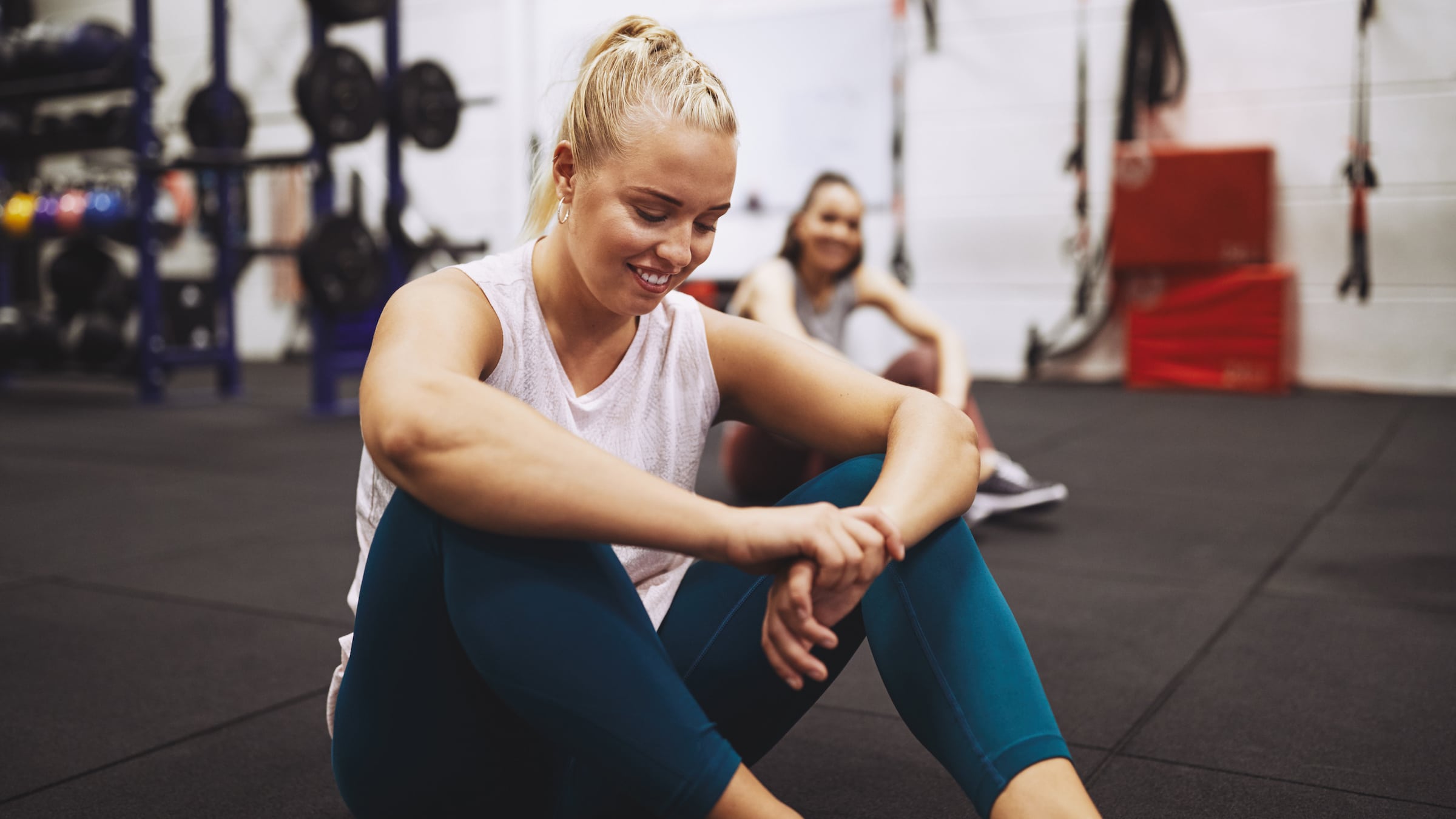Smiling woman resting on a gym floor after a workout