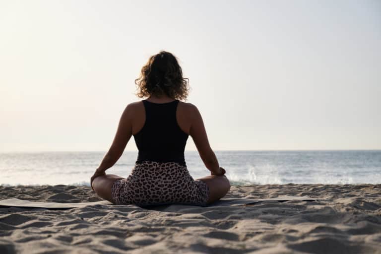 A woman practicing yoga at the sunrise on the beach