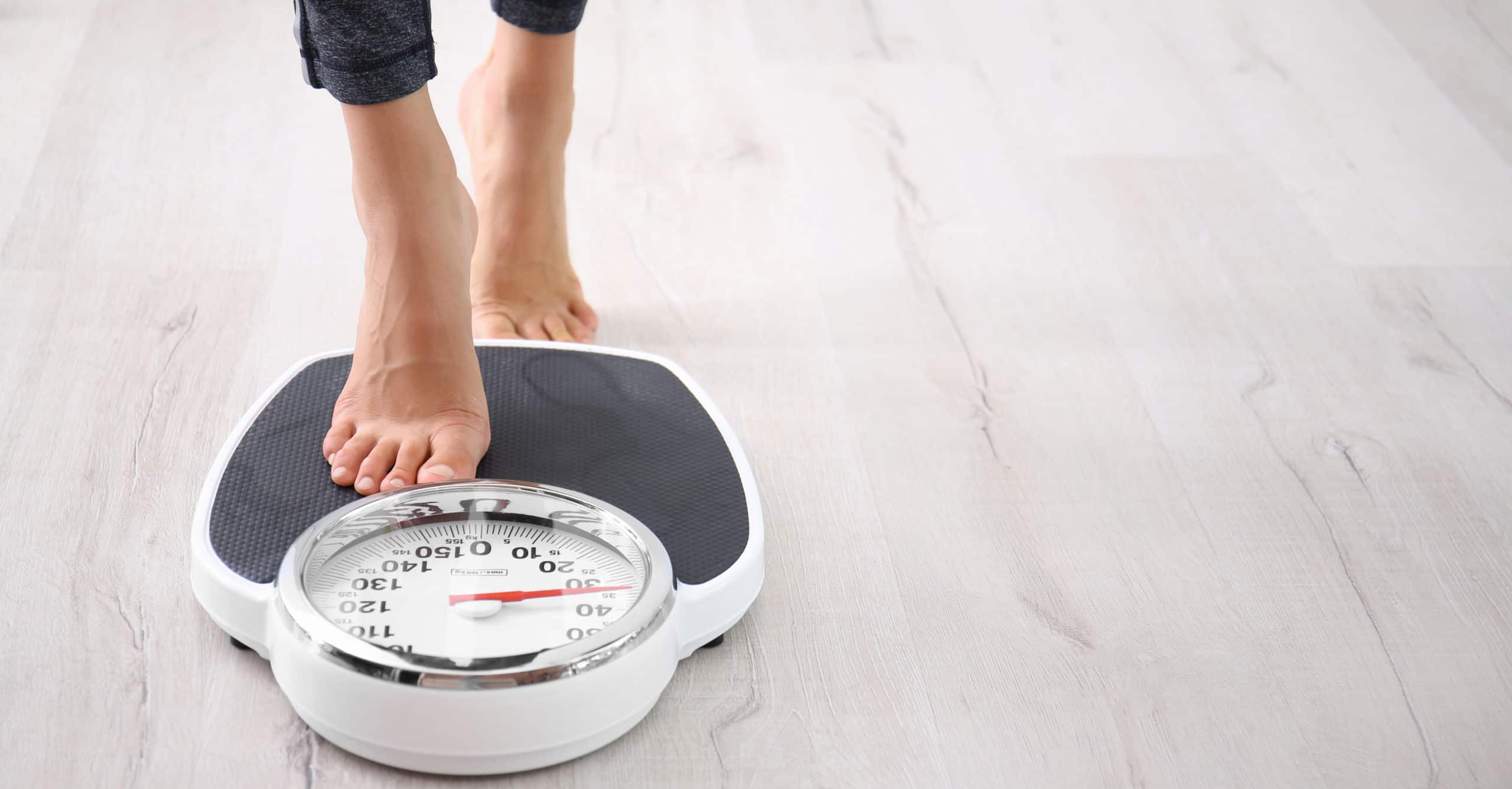 Woman measuring her weight using scales on floor