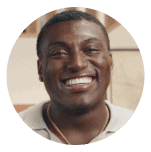 Smiling man in a light-colored shirt with a gold chain, set against a circular coral background. Represents positivity, confidence, and the supportive Noom community.