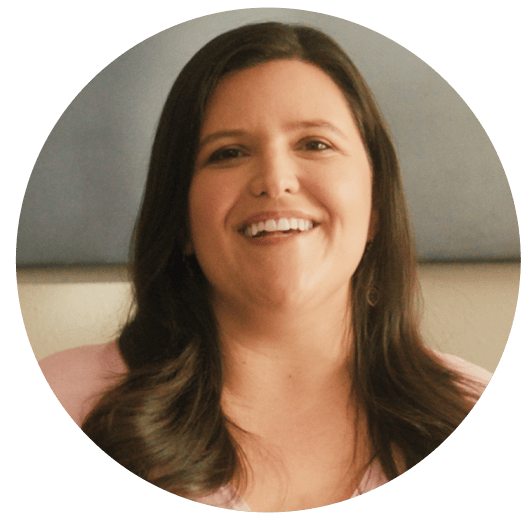Smiling woman with long dark hair wearing a light pink top, framed in a circular coral background. Represents warmth, encouragement, and Noom’s supportive wellness community.