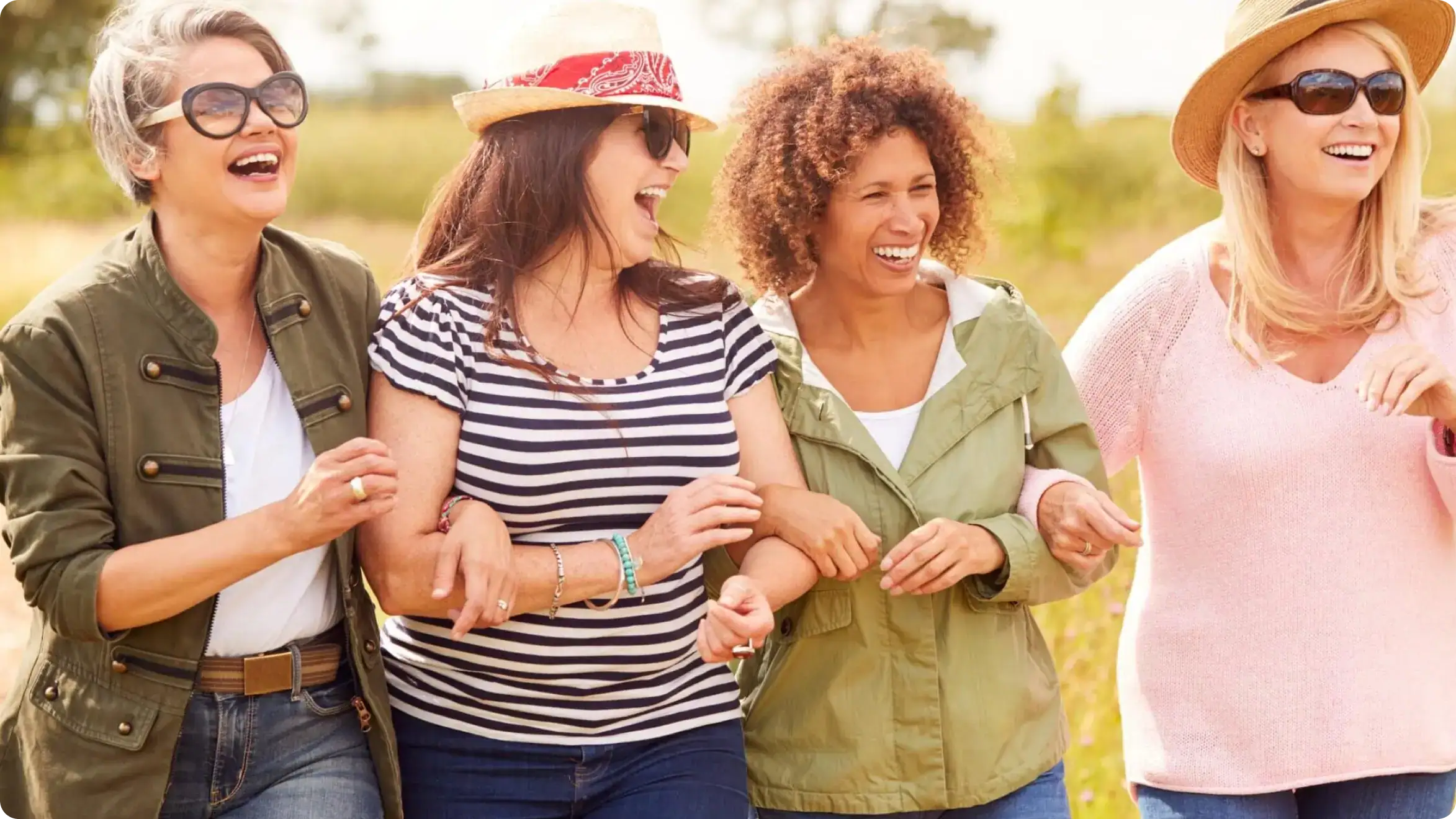 Four diverse middle-aged women smiling and walking arm-in-arm outdoors, symbolizing support, empowerment, and healthy lifestyle habits. Image relates to menopause and urinary incontinence—highlighting causes, treatments, and relief strategies for 2025, as part of Noom’s wellness and behavior-change program.